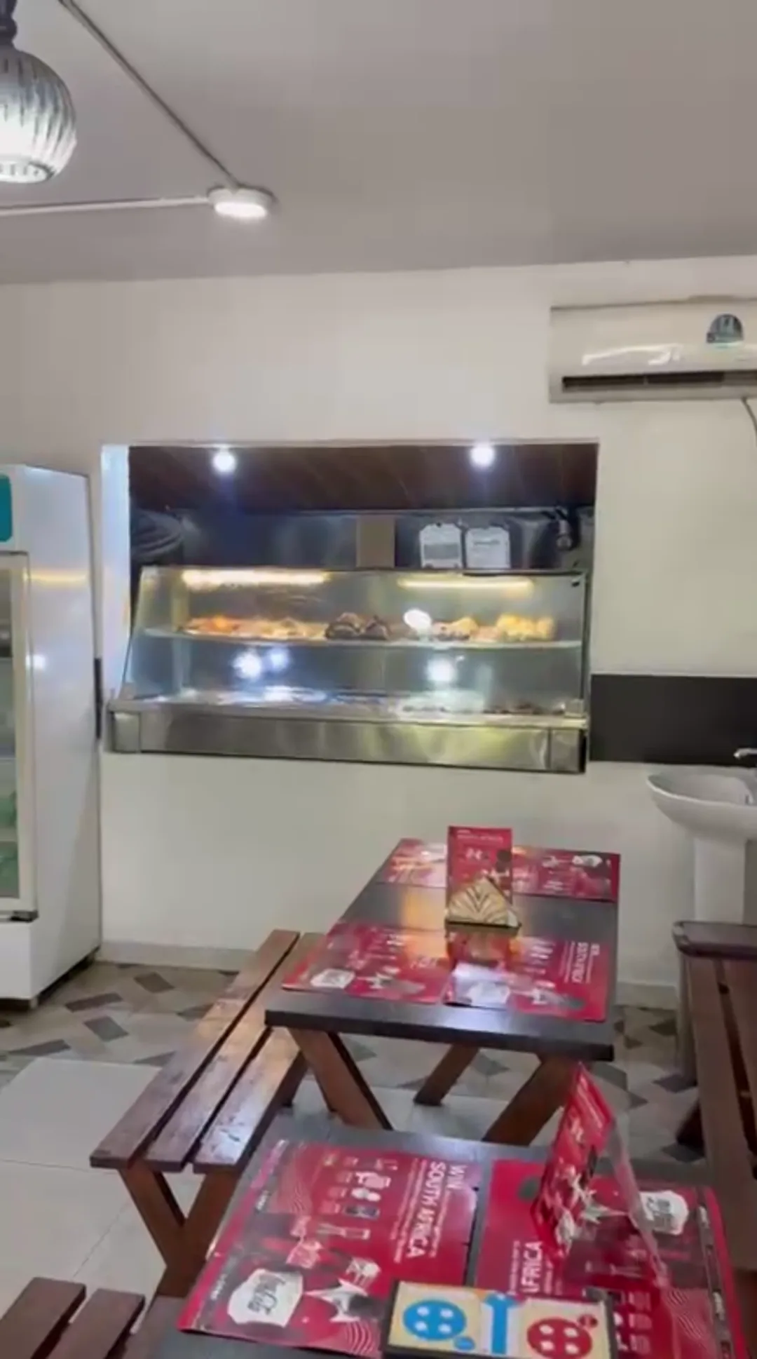 Inside Amala Station: wooden benches and tables facing the hot food display counter