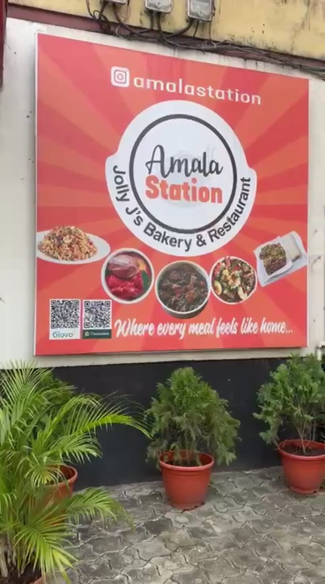 The orange Amala Station signboard with photos of jollof rice, stew and soups, outside the restaurant